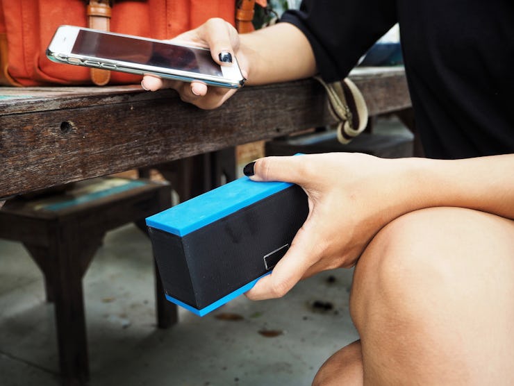 Woman using bluetooth speaker with smart phone