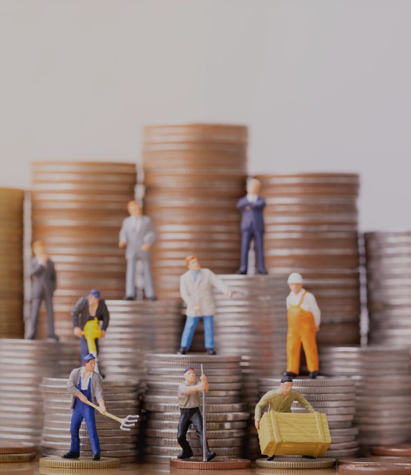 Miniature people standing on a pile of coins. Inequality and social class. Income and economic inequ...