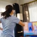A person with a ponytail and grey t-shirt does a dance workout online. Whether you're busting out mo...