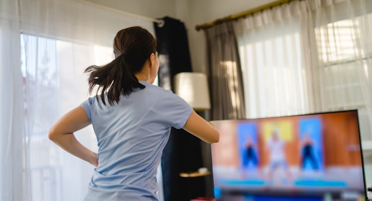 A person with a ponytail and grey t-shirt does a dance workout online. Whether you're busting out mo...