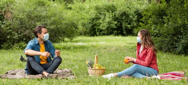 Couple have date during the coronavirus lockdown crisis. Man and woman in the park. Social distancin...