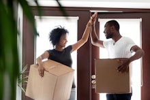 Happy young african american couple tenants give high five celebrate moving day in own house hold bo...