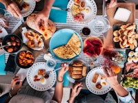 Above aerial view of group of friends having fun eating together at lunch or dinner with a table ful...