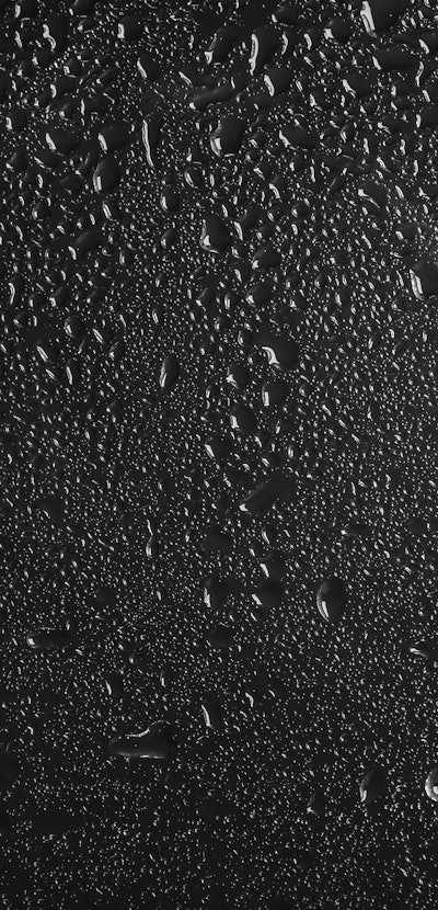 Glass with rain drops against dark background