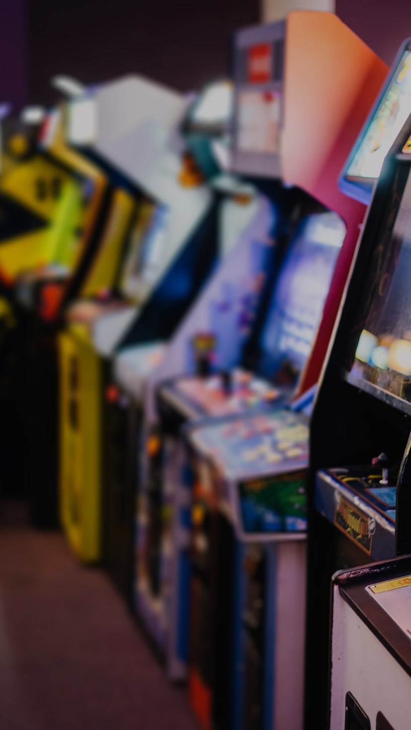 Old Vintage Arcade Games in a dark room and players playing video games in the background