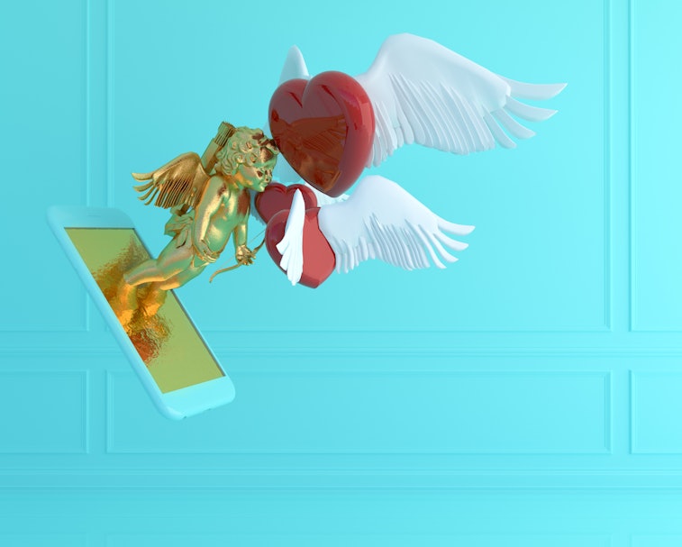 A golden Cupid emerges from the screen of a smartphone. There is a flying red heart with white wings...