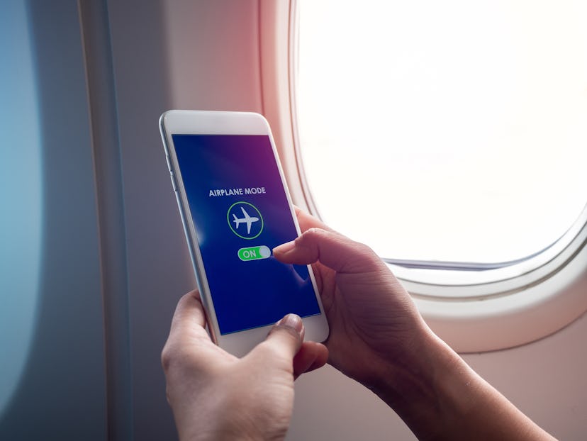 Flight mode concept. Finger sliding on screen for turned on airplane mode near the window on the air...