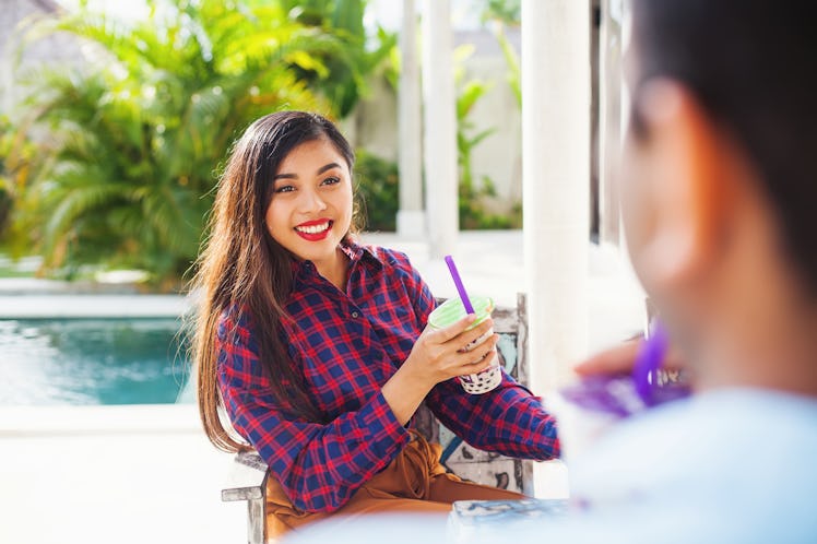 A happy woman relaxes outside on her porch with a bubble tea. 