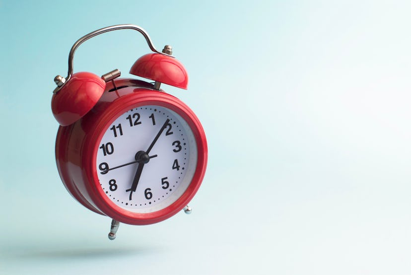 Red alarm clock. Flying alarm clock. Red alarm clock on a blue background.