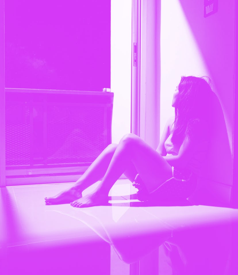 Sad and depressed young woman sitting on the floor in the living room looking outside the doors,sad ...