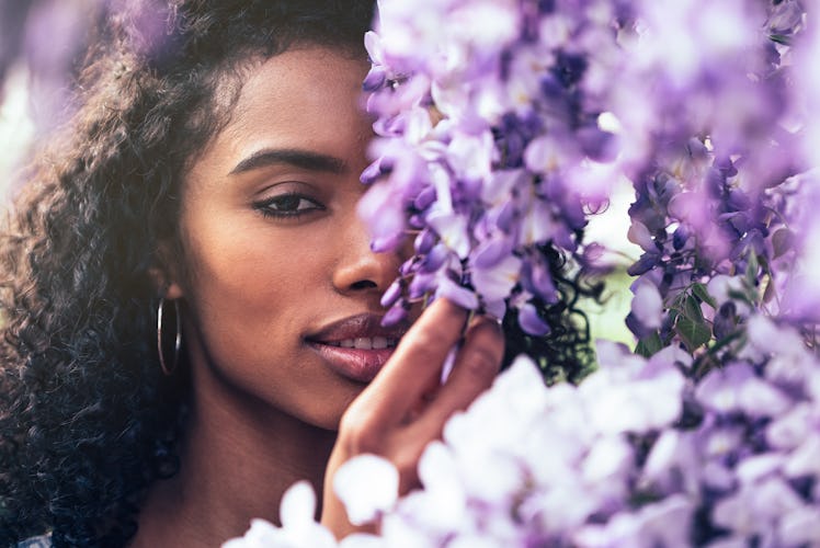 Thoughtful happy young black woman surrounded by flowers