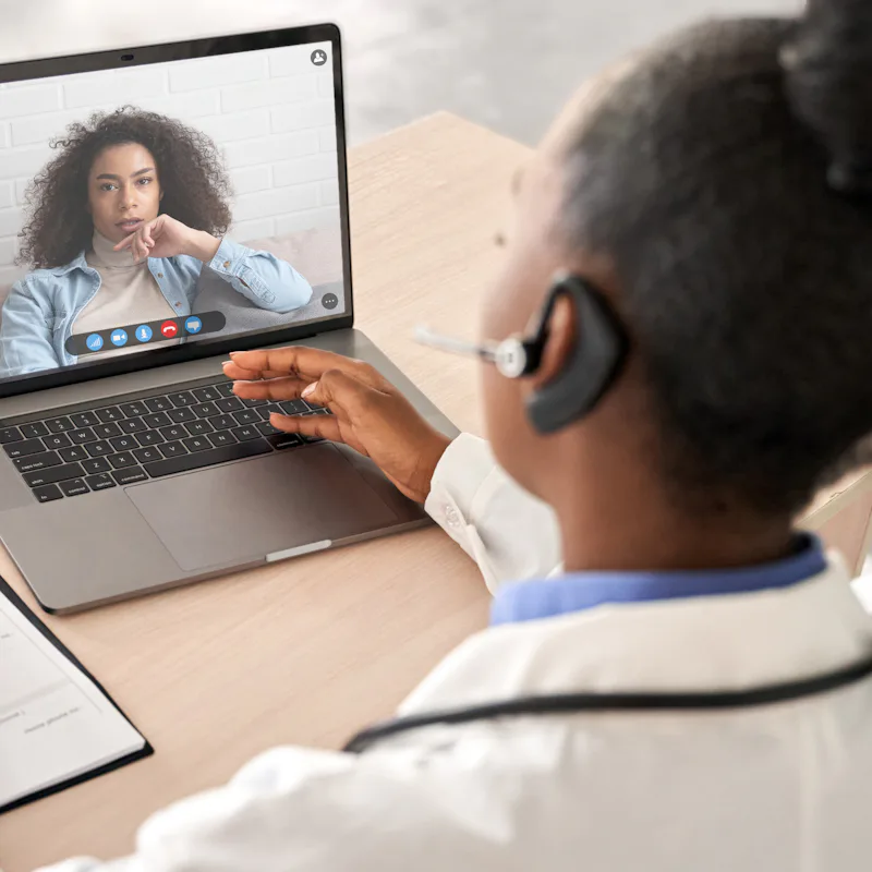 African doctor wear headset consult female black patient make online webcam video call on laptop scr...