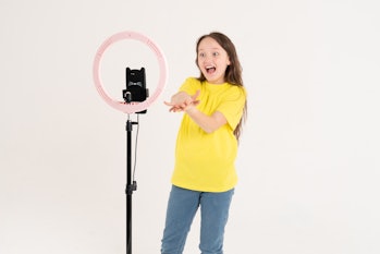 A teenage girl dances and shoots a video. Selfies. The phone is mounted on a tripod and the ring lam...