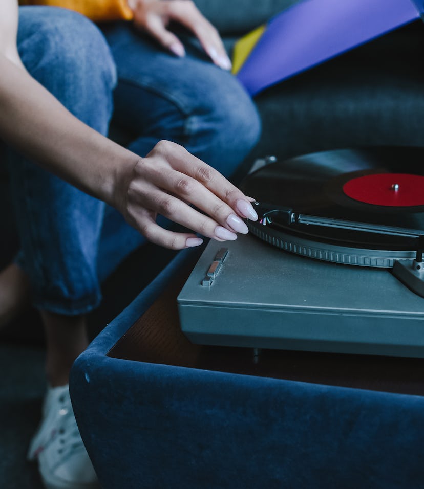 cropped image of mixed race girl turning on gramophone with retro vinyl at home