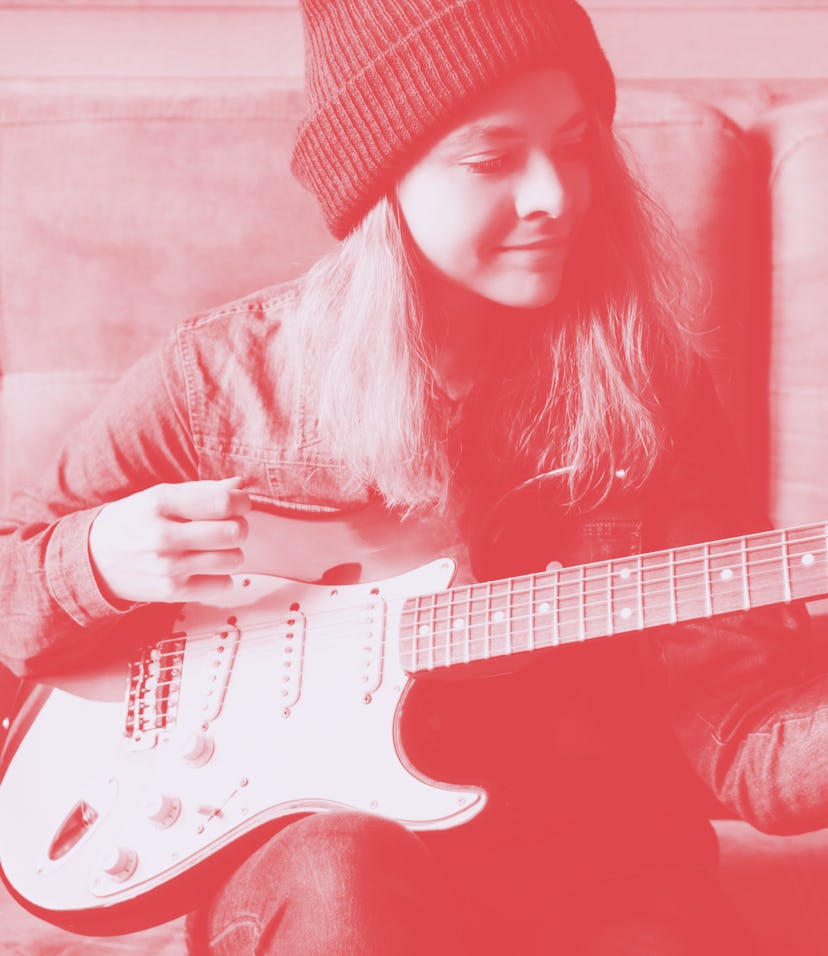 Young woman playing guitar. Music concept. Home atmosphere on background.