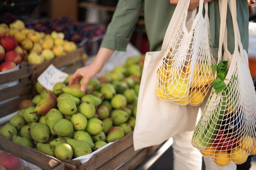 A woman chooses fruits and vegetables at farmers market. 