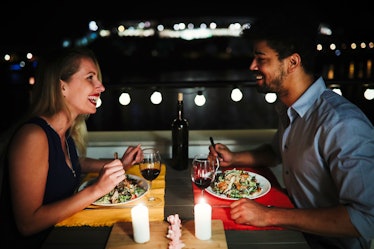 A happy couple laughs while enjoying date night dinner outside.