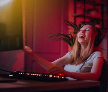 The girl plays computer games at home. A young woman is watching a video in headphones with a microp...