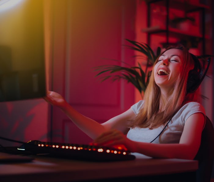 The girl plays computer games at home. A young woman is watching a video in headphones with a microp...
