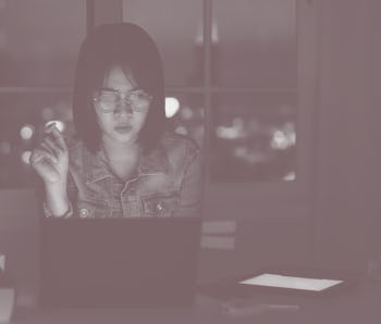 Candid of young attractive asian female student sitting on desk with smart digital gadget looking at...