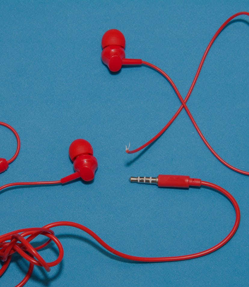 Red broken torn headphones on classic blue background.