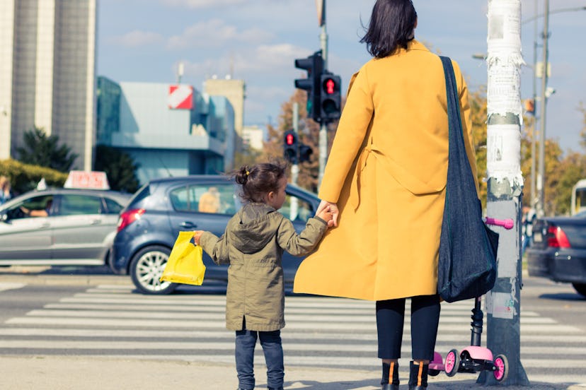 child and grown up holding hands, waiting to cross the street