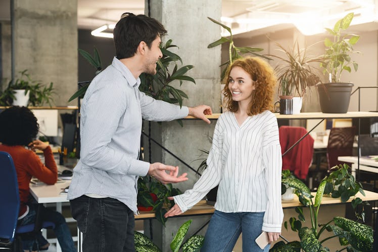 Young man and woman colleagues talking during working time in coworking space