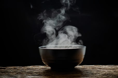 Steam of hot soup with smoke wood bowl on dark background.selective focus.hot food concept