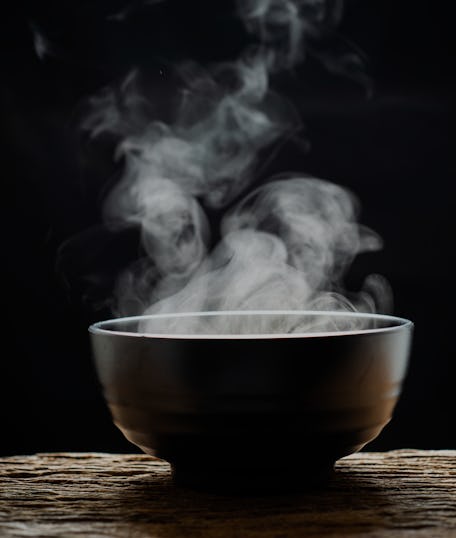 Steam of hot soup with smoke wood bowl on dark background.selective focus.hot food concept