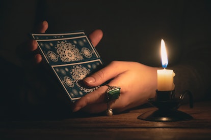 Fortune teller reading a future by tarot cards in the light of candle concept.