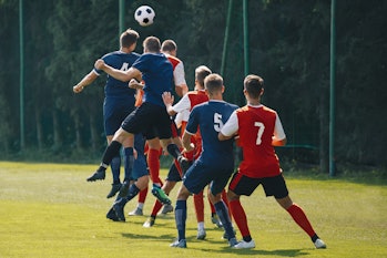 Soccer players heading the ball in competition. Football adult game. Players in two teams compete fo...