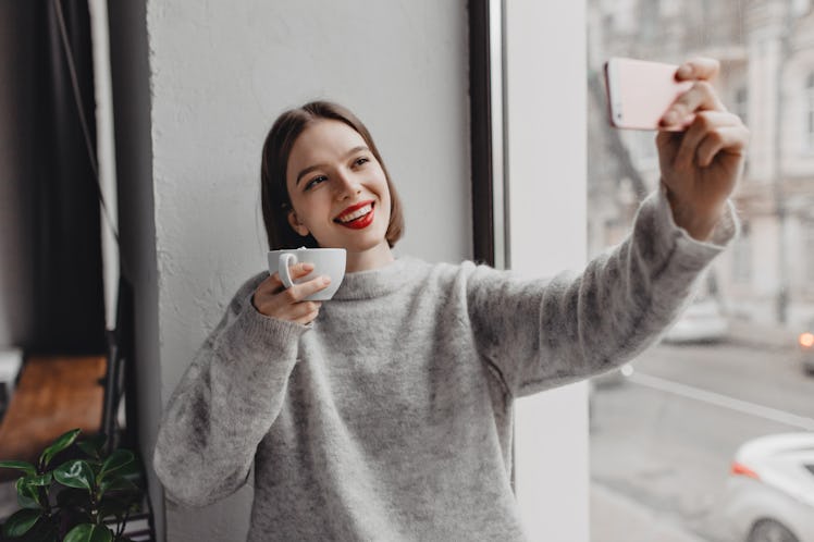 Picture of brown-eyed lady with red lipstick dressed in cashmere oversized outfit taking selfie with...