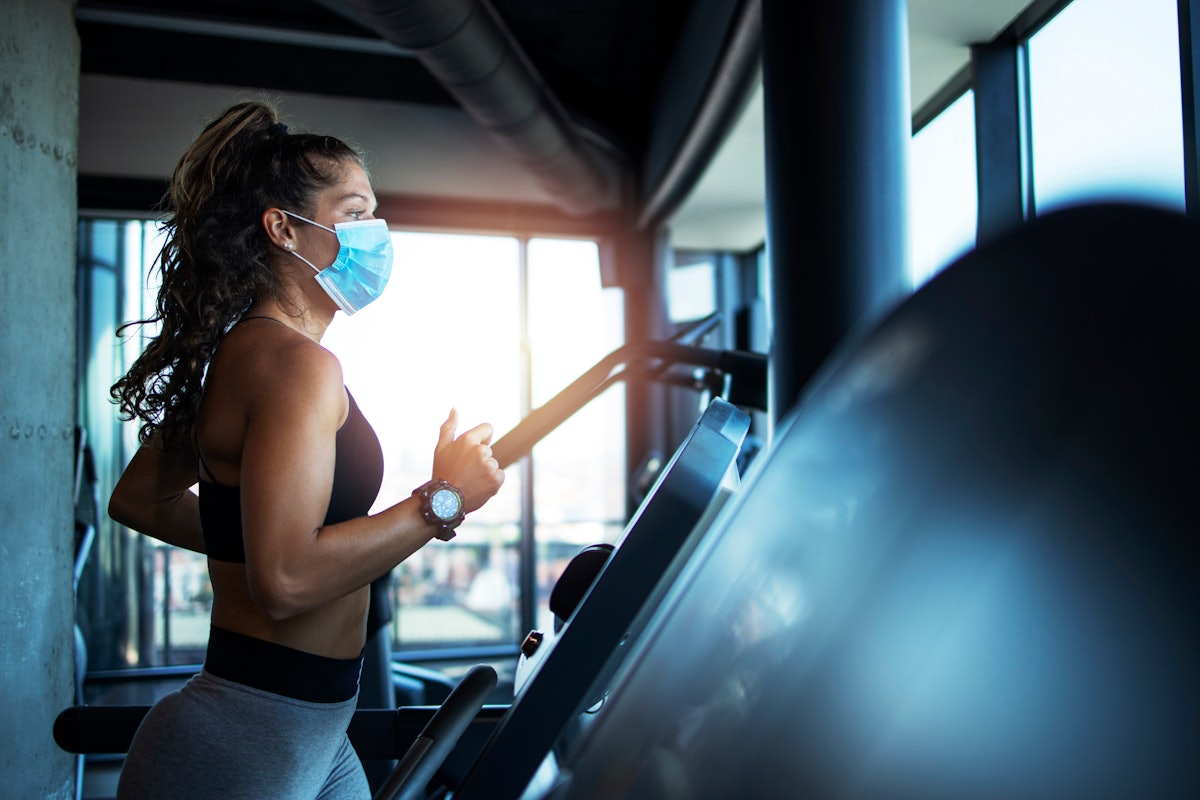 woman wearing a face mask doing HIIT at the gym