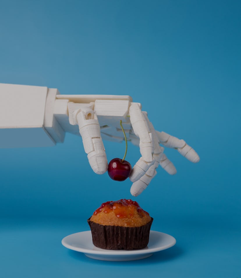 Chef robotic assistant in kitchen technology. Robot hand decorating sweet cupcake with fresh cherry,...