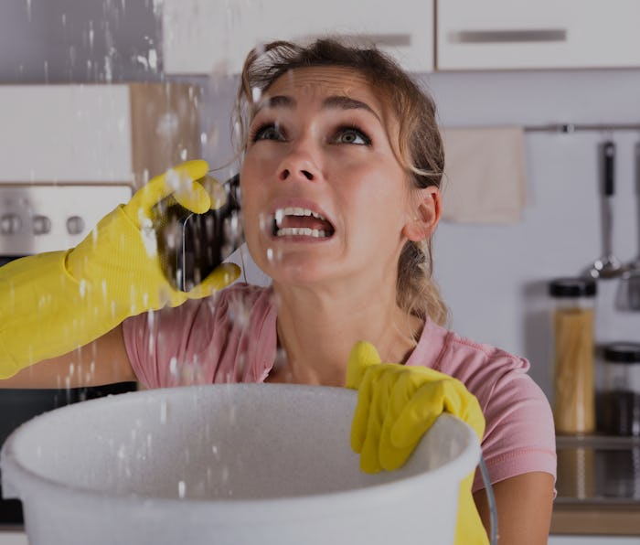 Shocked Woman Calling Plumber While Collecting Water Leaking From Ceiling Using Utensil