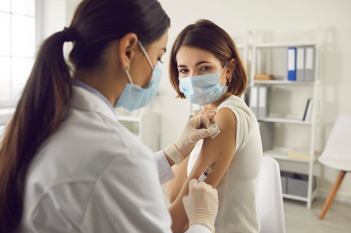Vaccination, immunization, disease prevention concept. Woman in medical face mask getting Covid-19 o...
