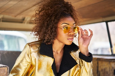 stylish edgy african american woman wearing golden jacket and sunglasses in old van