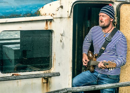 Old salt man playing guitar on his rusted ship