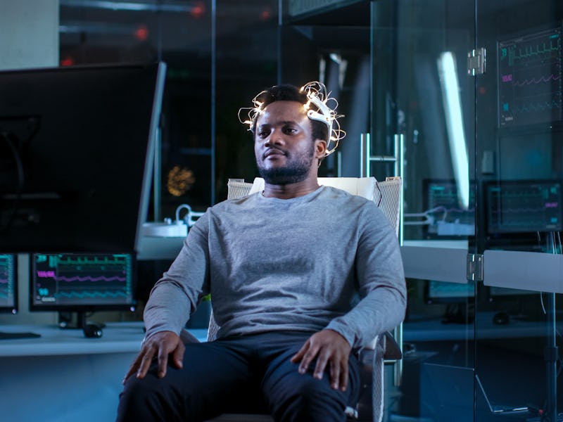 Man Wearing Brainwave Scanning Headset Sits in a Chair while Watching Stimulating Images on Display ...