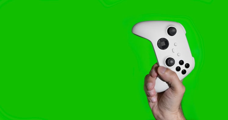 A man holding a white next generation controller with a green background