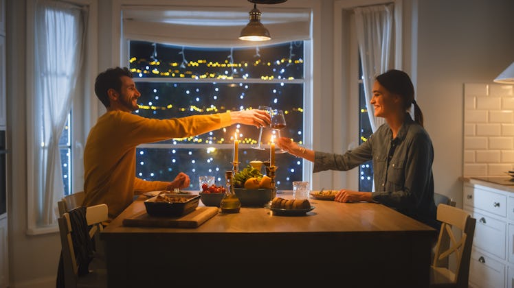 Happy Young Couple in Love Have Romantic Dinner, Toasting Each other with Glasses of Wine, Eating Ta...