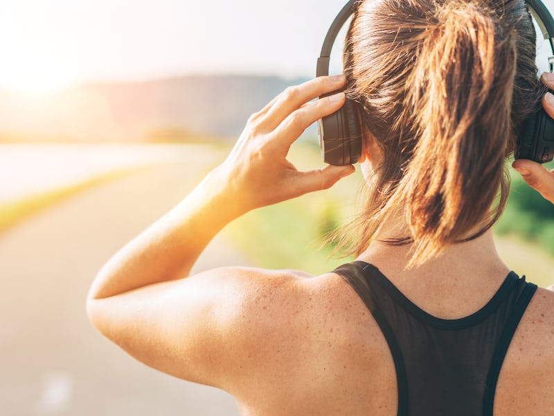 Close up image of teenager adjusting wireless headphones before starting jogging and listening to m...