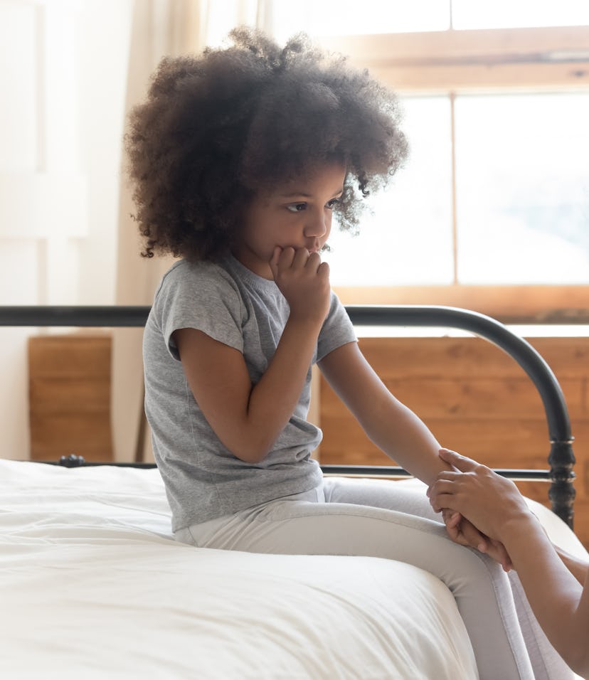 Caring worried african american mother holding hand of sad little mixed race daughter talking giving...