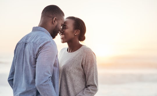 What love song quotes would you use for this smiling young Black couple smiling while standing foreh...