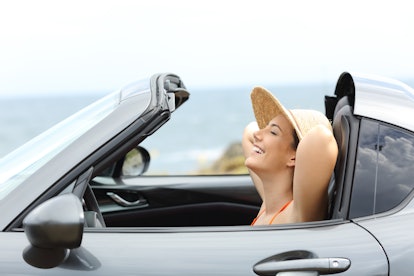 Side view portrait of a relaxed driver resting inside a convertible car on summer vacation