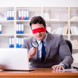 Blindfold businessman sitting at desk in office