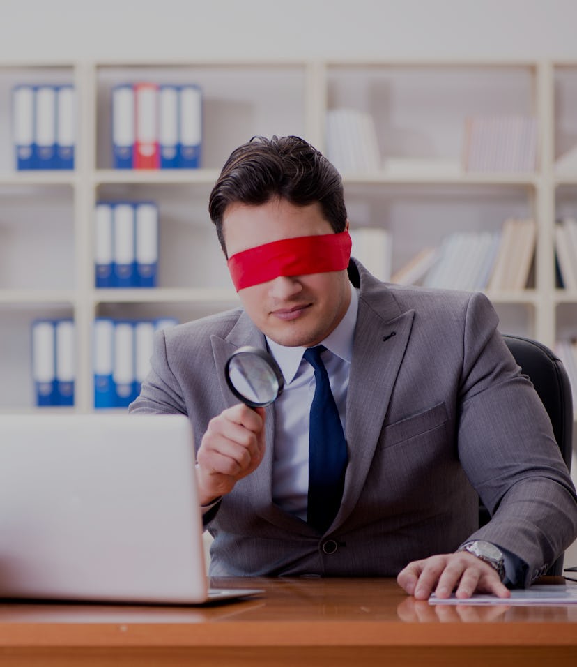 Blindfold businessman sitting at desk in office