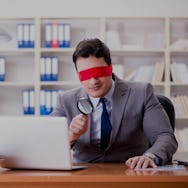 Blindfold businessman sitting at desk in office