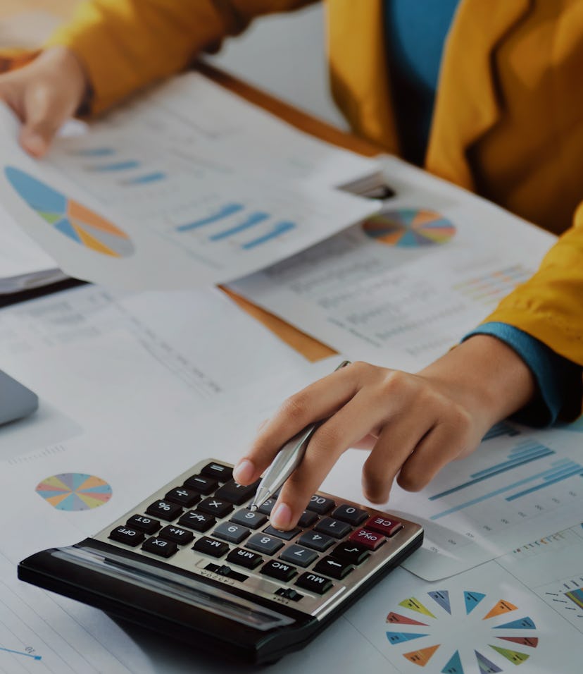 Woman accountant use calculator and computer with holding pen on