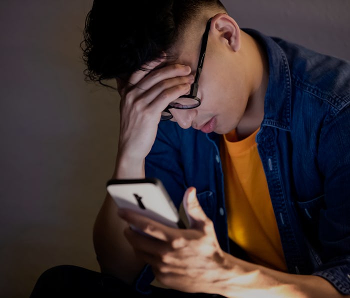 asian man is upset while using smart phone outdoor in the evening